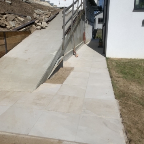 Færdig belægning ved adgangsvej med rampe og niveauforskel ved hus