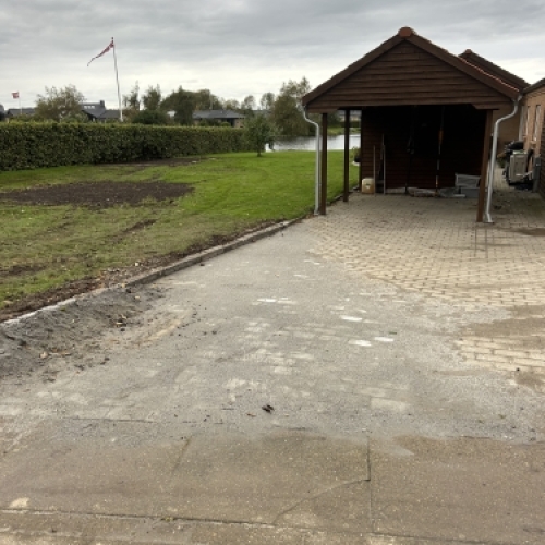 Indkørsel og belægning ved carport med pæn afslutning mod græs