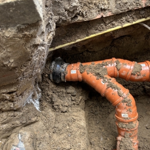 Kloakmester udfører kloakarbejde omkring trappe og fundament med fokus på holdbarhed