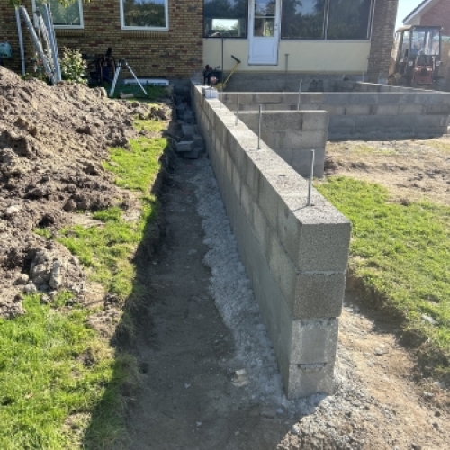 Opbygning af støttemur med betonblokke til niveauforskel i haven