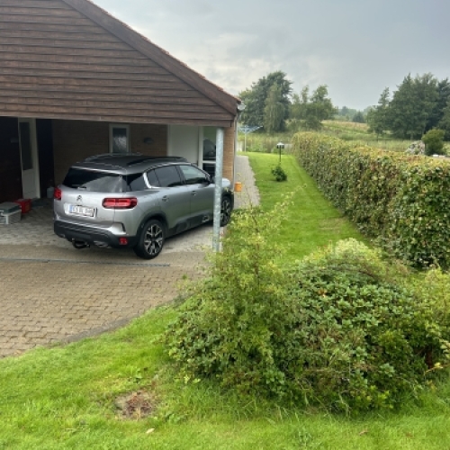 Indkørsel og belægning ved carport med ryddelige linjer og afslutninger