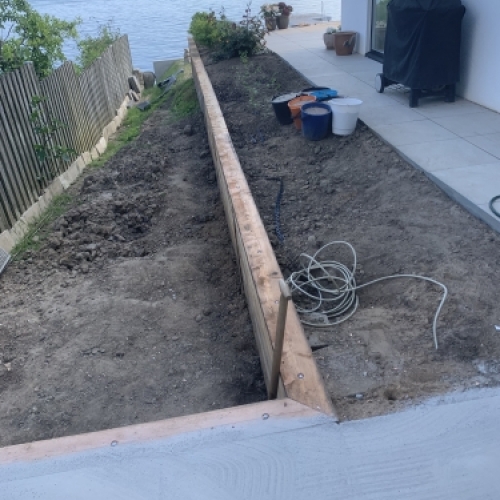 Kantopbygning til belægning ved terrasse med jordarbejde langs vandet