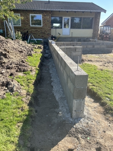 Opbygning af støttemur med betonblokke til niveauforskel i haven