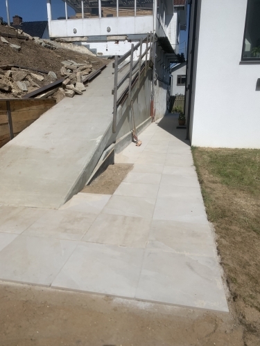Færdig belægning ved adgangsvej med rampe og niveauforskel ved hus