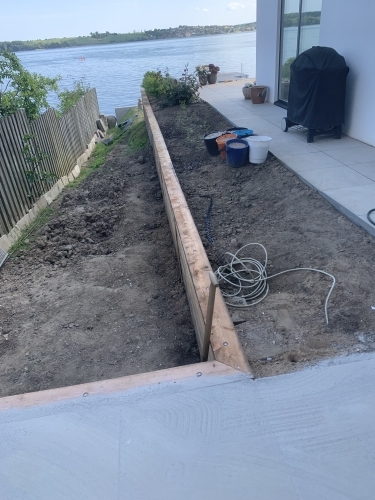 Kantopbygning til belægning ved terrasse med jordarbejde langs vandet