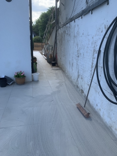 Belægning langs husmur under udførelse med fokus på fald og afvanding