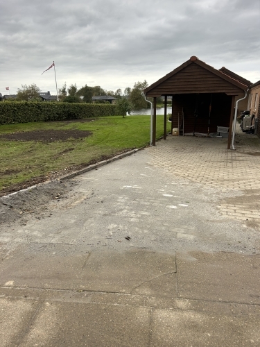 Indkørsel og belægning ved carport med pæn afslutning mod græs