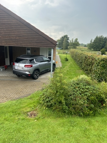 Indkørsel og belægning ved carport med ryddelige linjer og afslutninger