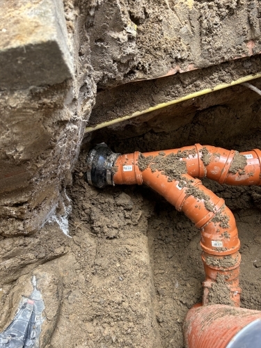 Kloakmester udfører kloakarbejde omkring trappe og fundament med fokus på holdbarhed